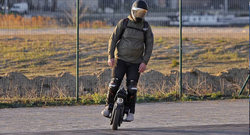 Una persona circulando en un vmp monociclo con casco de protección